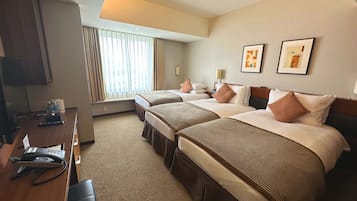 A hotel room with two beds, a desk with a telephone, and a window with curtains.