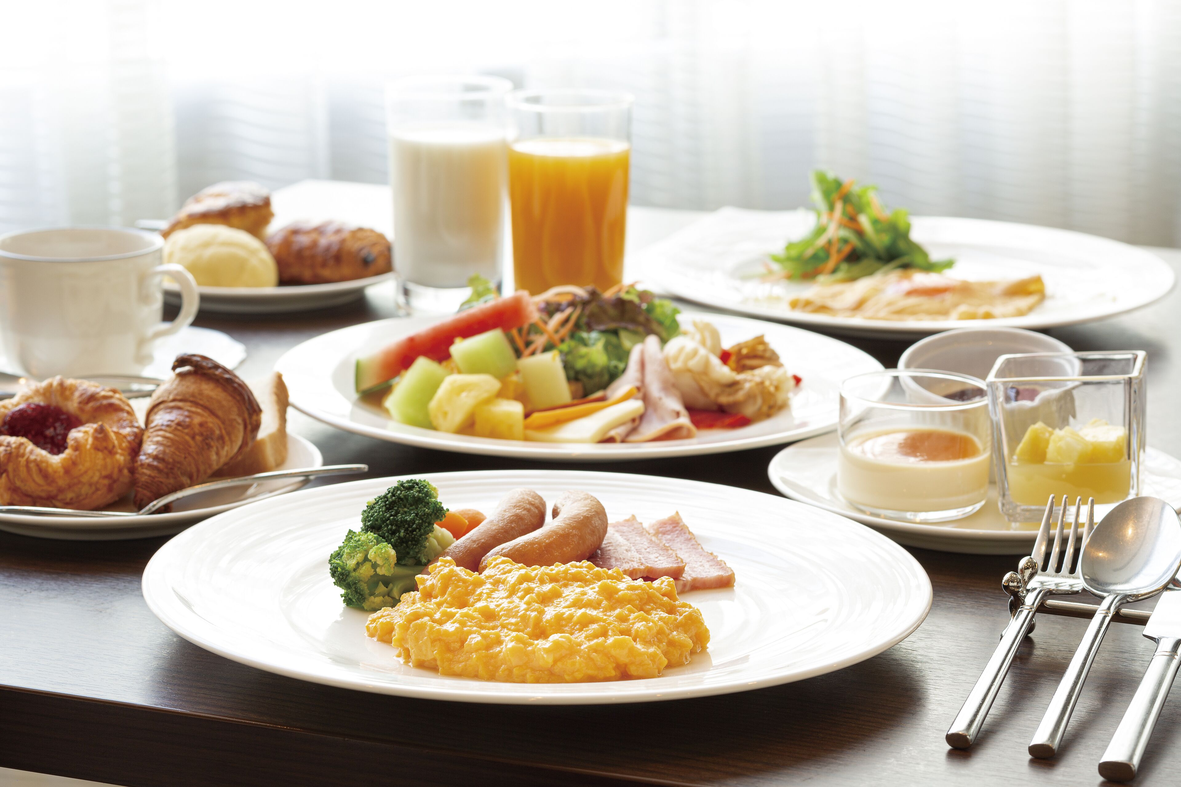 A breakfast setting with various dishes including eggs, sausages, and vegetables.