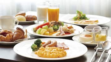 Un desayuno con diferentes platos, como huevos, salchichas y verduras.