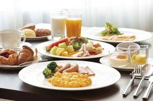 Un desayuno con diferentes platos, como huevos, salchichas y verduras.