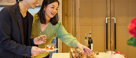 A couple standing by a table with a variety of small dishes and bottles, likely a tasting or buffet setup.