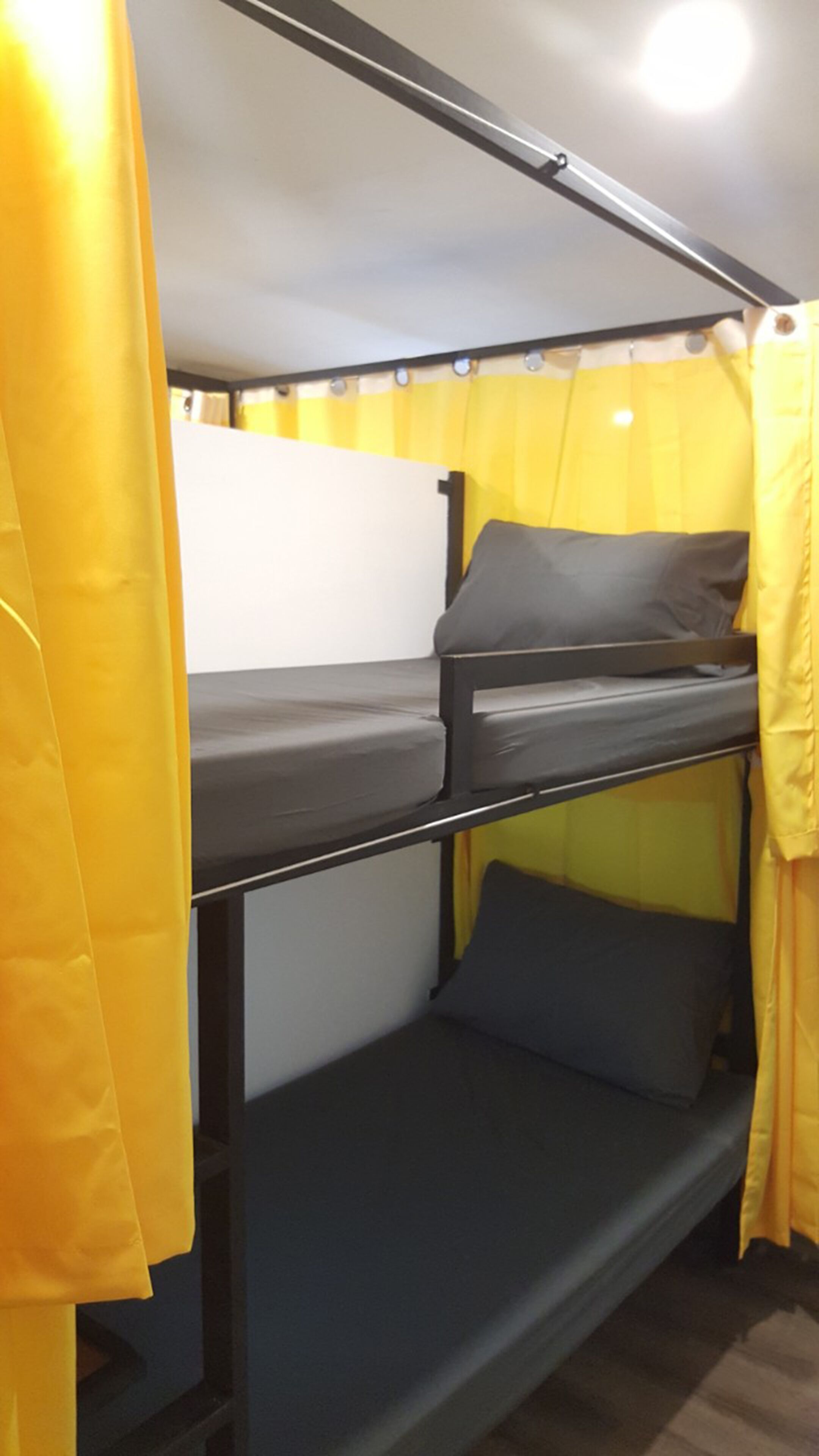 A bunk bed with yellow curtains and a white headboard.
