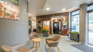A hotel reception area with a B&B shop, seating, and a map display. - B&B HOTEL Cholet Sud (Cholet)