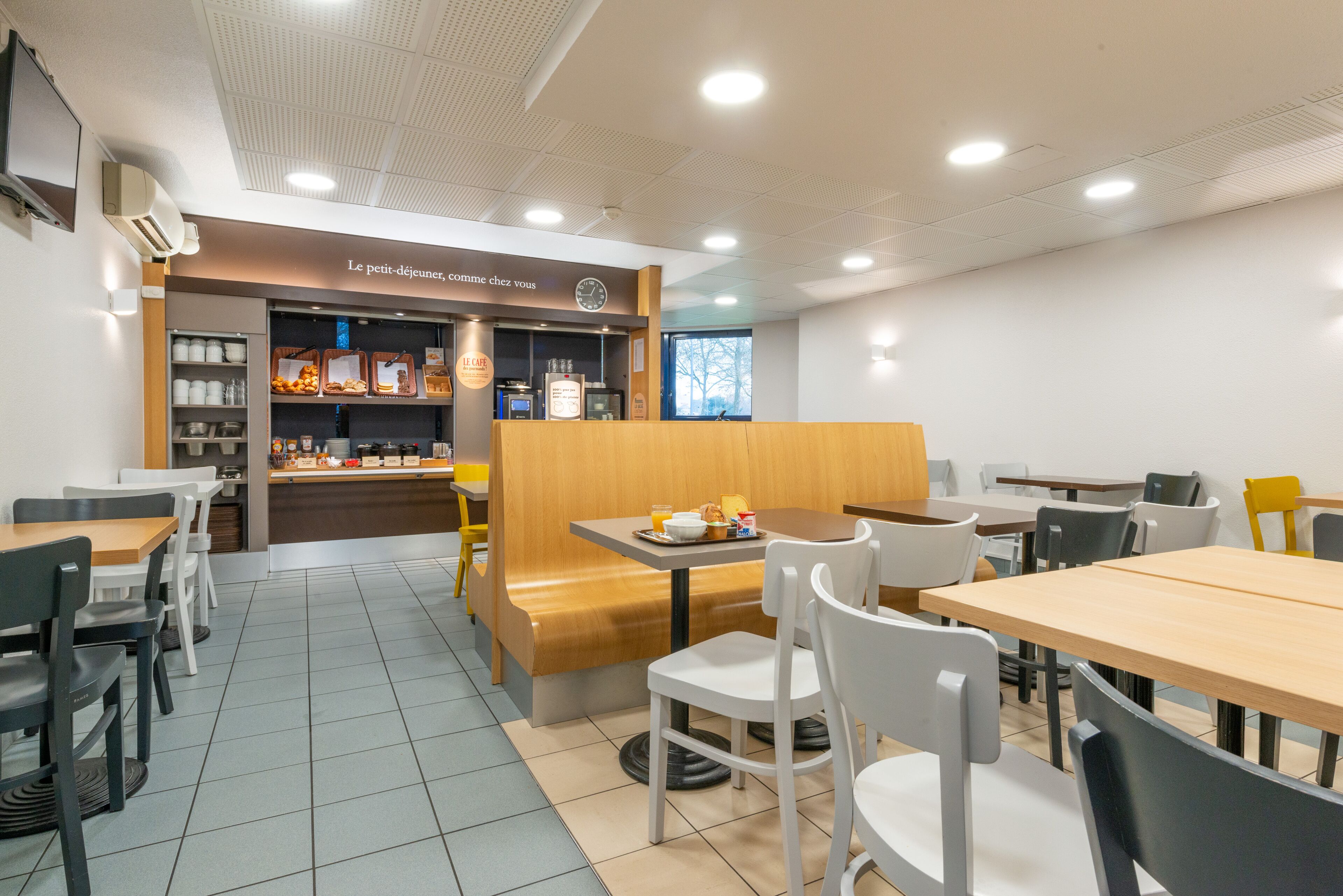 A café with a wooden counter, white chairs, and a tiled floor.