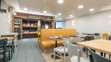 A café with a wooden counter, white chairs, and a tiled floor.