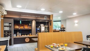A café with a breakfast buffet, seating area, and a clock on the wall. - B&B HOTEL Cholet Sud (Cholet)