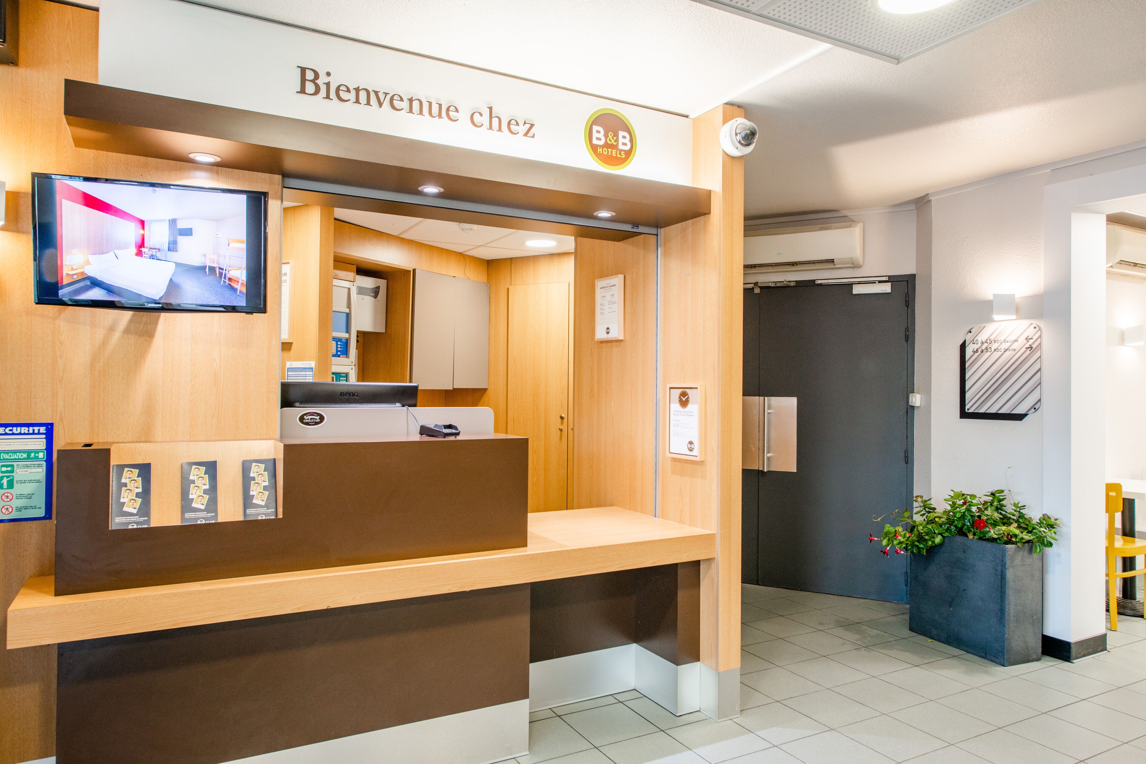 A reception desk with a television, a B&B logo, and a welcome sign.