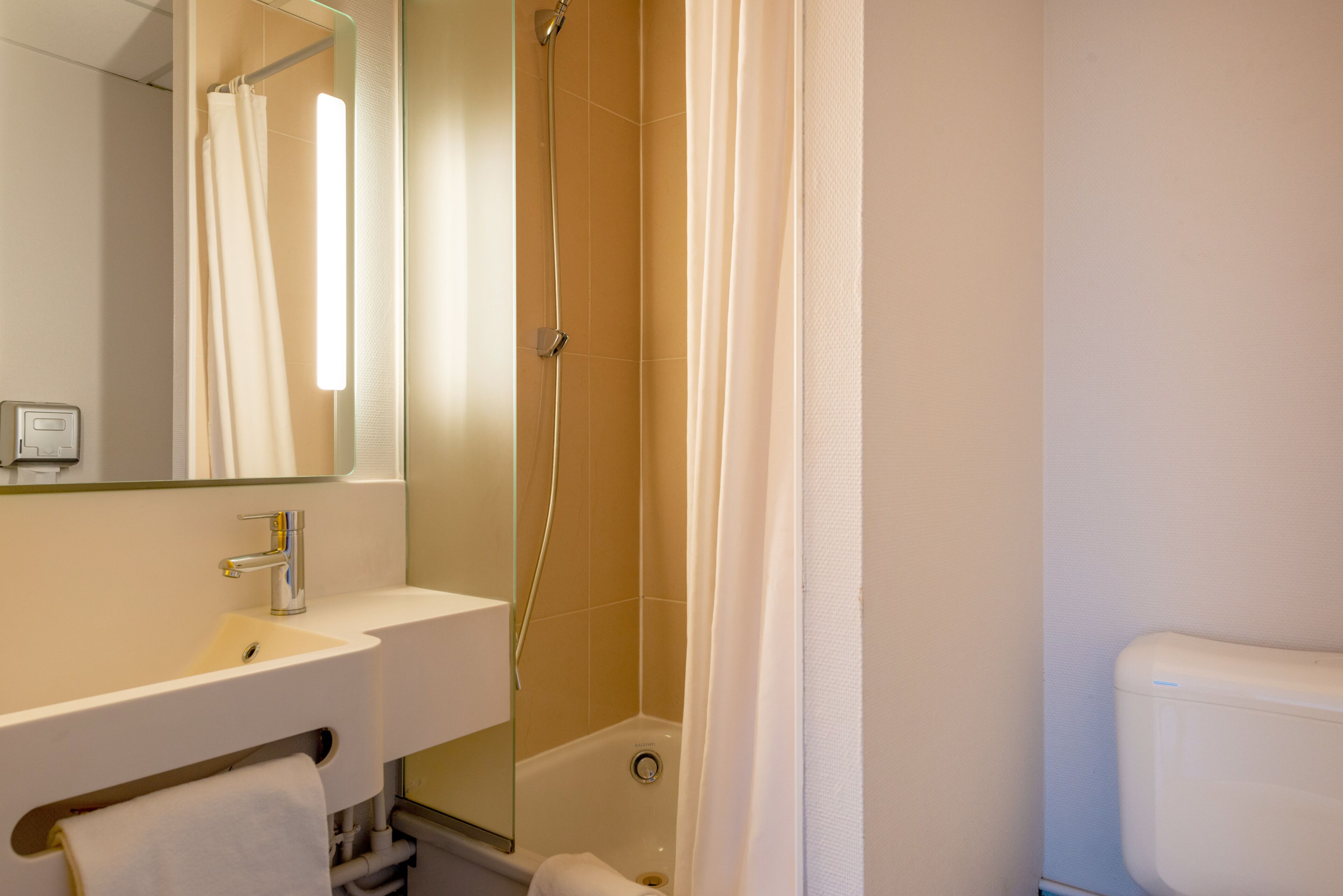 Ein Badezimmer mit Waschbecken, Spiegel, Dusche und Toilette.