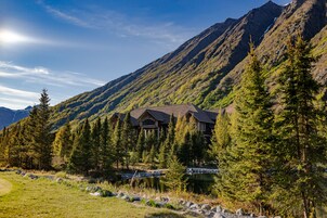 A lodge with a large central building surrounded by trees and mountains.