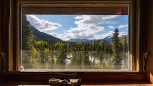Una ventana con vistas a un paisaje montañoso, un lago y un bosque.
