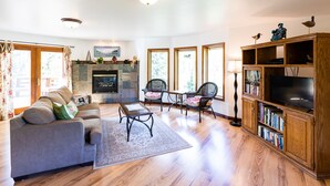 Una sala de estar con sofá, sillas, chimenea, televisor y estantería.