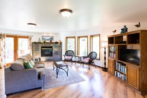 A living room with a sofa, chairs, a fireplace, a television, and a bookshelf.
