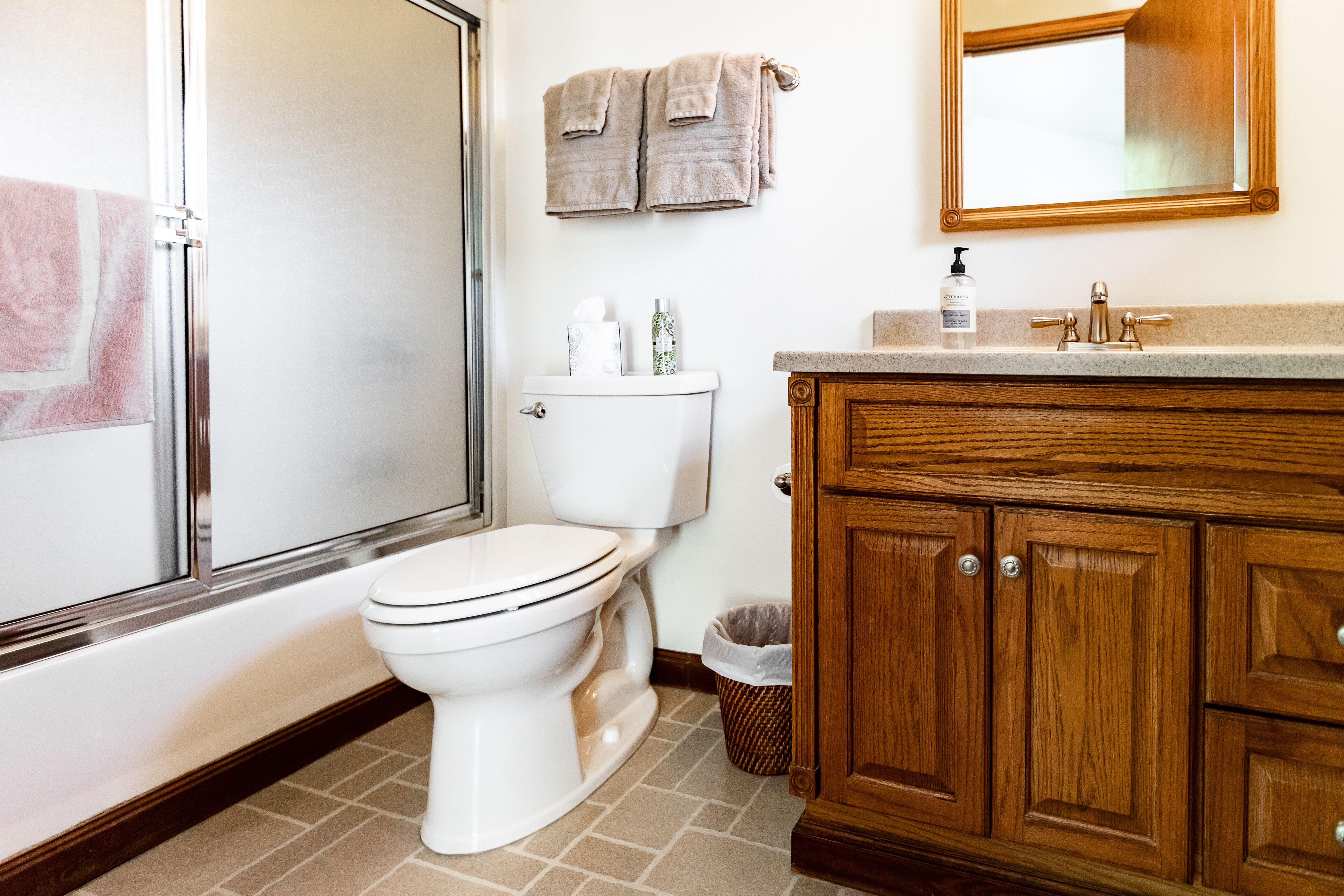 Une salle de bain équipée de toilettes, d’un lavabo, d’un miroir et d’un meuble en bois.