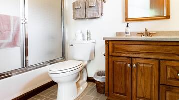 Une salle de bain équipée de toilettes, d’un lavabo, d’un miroir et d’un meuble en bois.