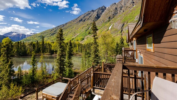 Terraza de madera con vista a un lago y montañas.