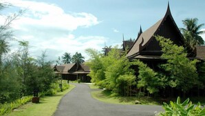 A pathway leading to traditional-style buildings surrounded by lush greenery and palm trees. - Takolaburi Cultural Resort (Takua Pa)