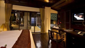 A hotel room with a bed, a desk with a chair, a television, and a view of the outside. - Takolaburi Cultural Resort (Takua Pa)