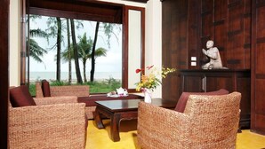 A room with wicker furniture, a statue, and a view of palm trees and the ocean. - Takolaburi Cultural Resort (Takua Pa)