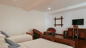 A bedroom with two beds, a wooden desk, a chair, a television, and a ceiling fan.