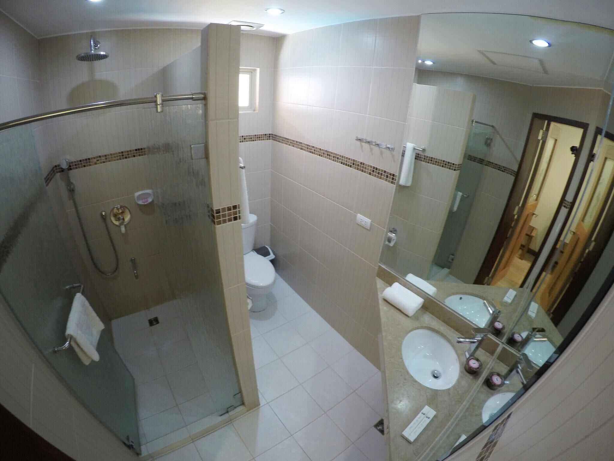 Un baño con ducha acristalada, inodoro y zona de lavamanos con espejos.