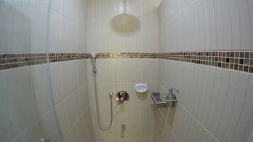 A small, tiled shower stall with a handheld showerhead, a wall-mounted toilet, and a sink.