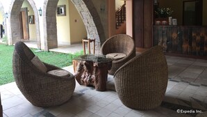 Un patio con mobiliario de mimbre, arcos de piedra y una escalera de madera.