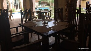 Un restaurante con terraza, arcos de piedra y vistas a una piscina. Las mesas están dispuestas con copas de vino y cubiertos.