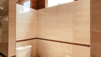 A bathroom with a toilet, a bidet, and a window.