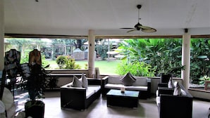 An indoor seating area with sofas and a coffee table, a ceiling fan, and a view of a garden with plants and a birdcage. - Chali Beach Resort and Conference Center (Cagayan de Oro)