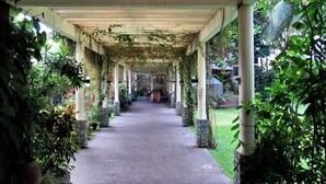 A covered walkway with stone pillars, surrounded by lush greenery and plants. - Chali Beach Resort and Conference Center (Cagayan de Oro)