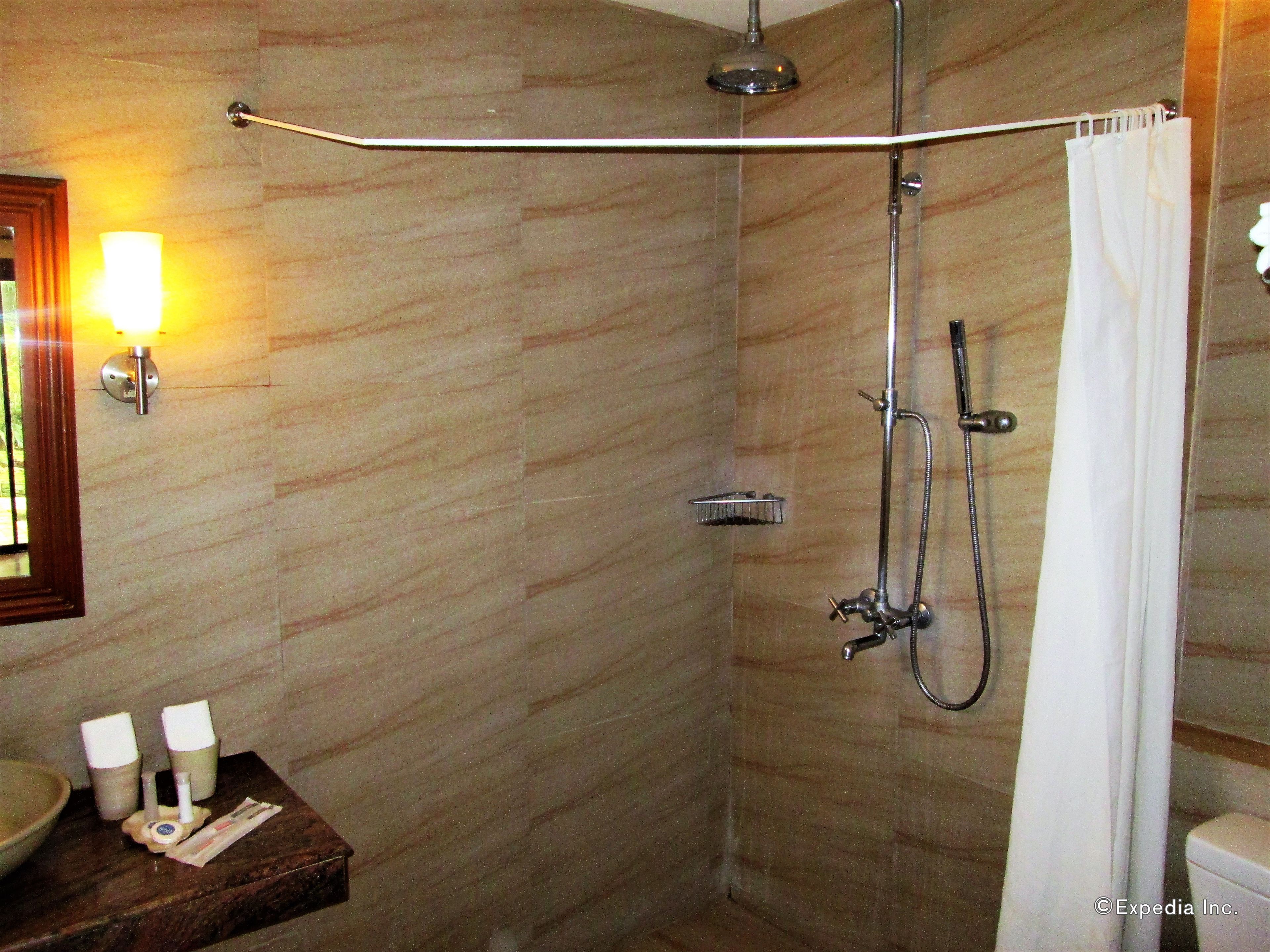 Un baño con ducha, toallero, lavabo e iluminación en la pared.