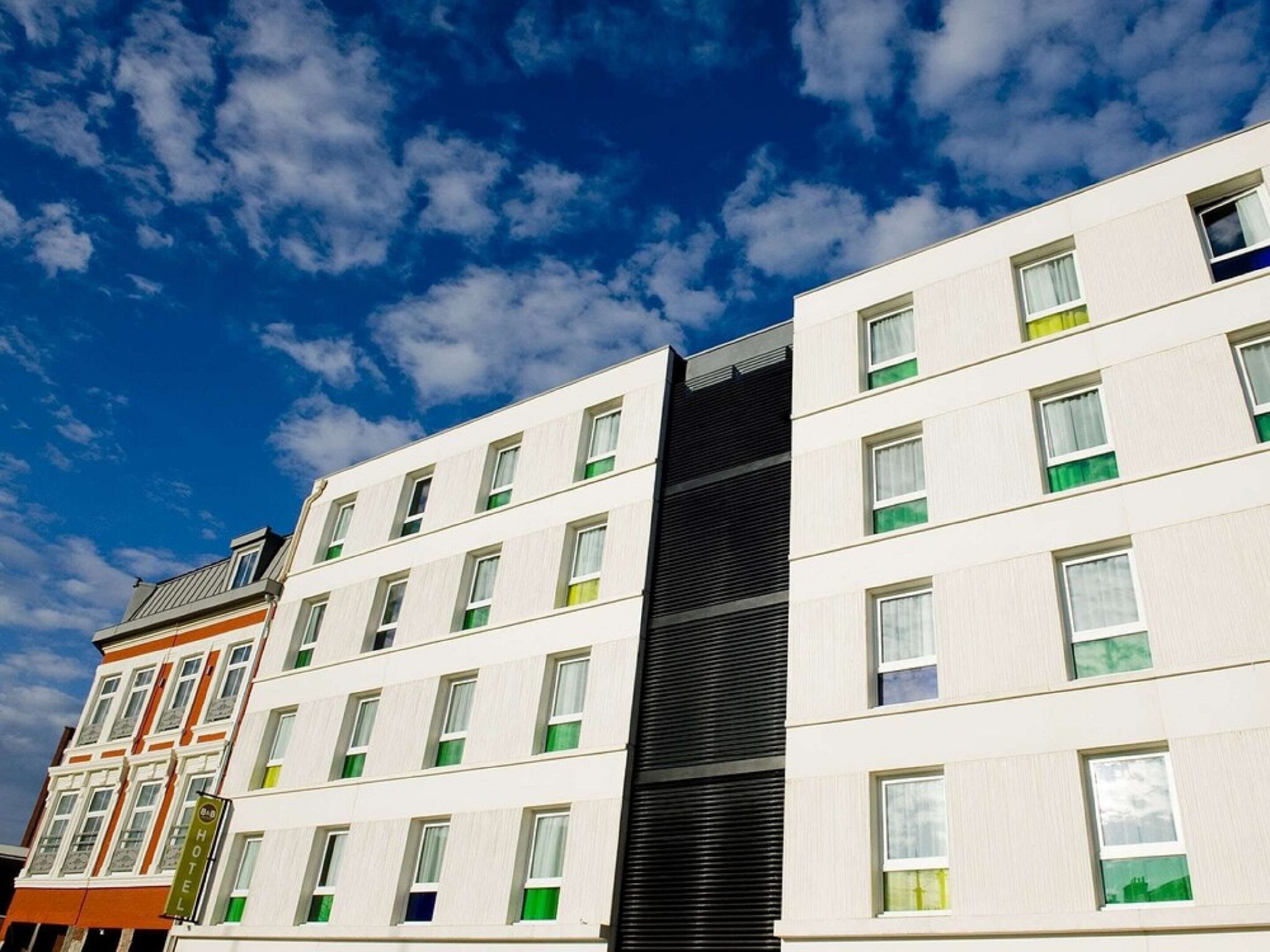 A modern hotel with multiple floors, large windows, and a prominent black vertical feature.