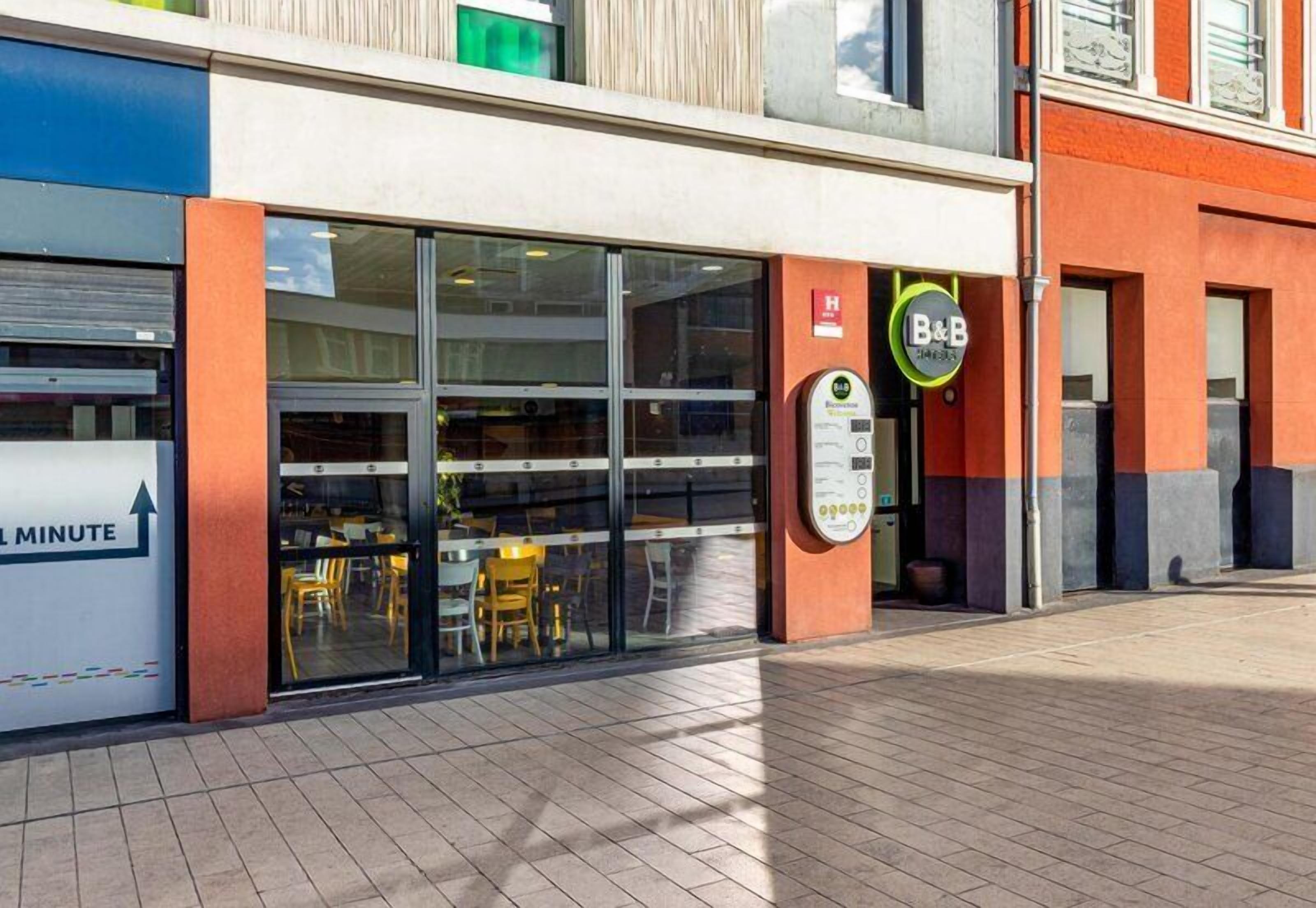 A modern building with a glass facade, a B&B sign, and a visible entrance.