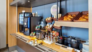 Un bufé de desayuno con cafeteras, pan, bollería y acompañamientos.
