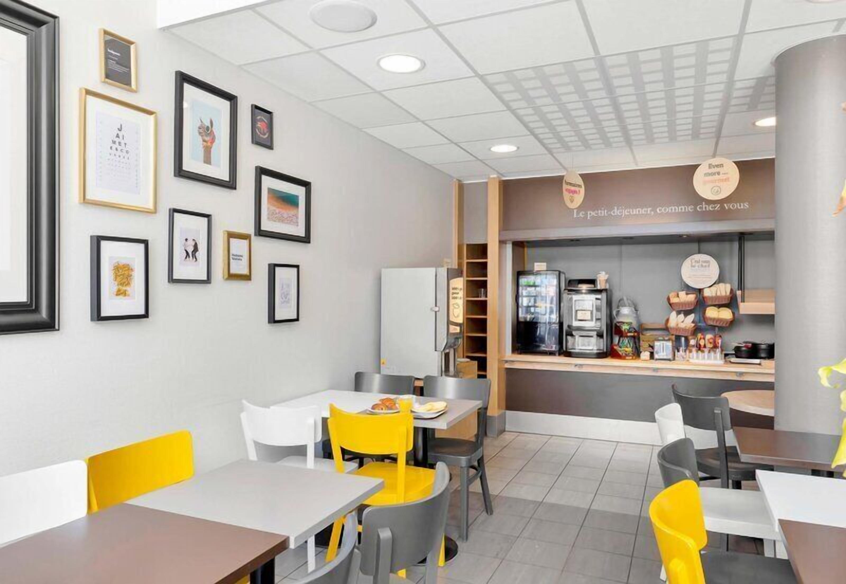 Un caffè con tavoli e sedie, quadri appesi alle pareti e un bancone con prodotti alimentari.