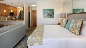 Ein Hotelzimmer mit Bett, einer Sitzecke, einer Küchenzeile und einem Bild an der Wand.