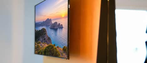 A flat-screen TV mounted on a wall displaying a scenic landscape.
