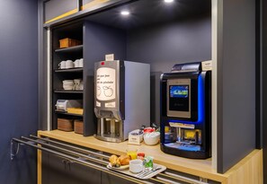 A breakfast bar with a coffee machine, a refrigerator, and a self-service beverage dispenser.