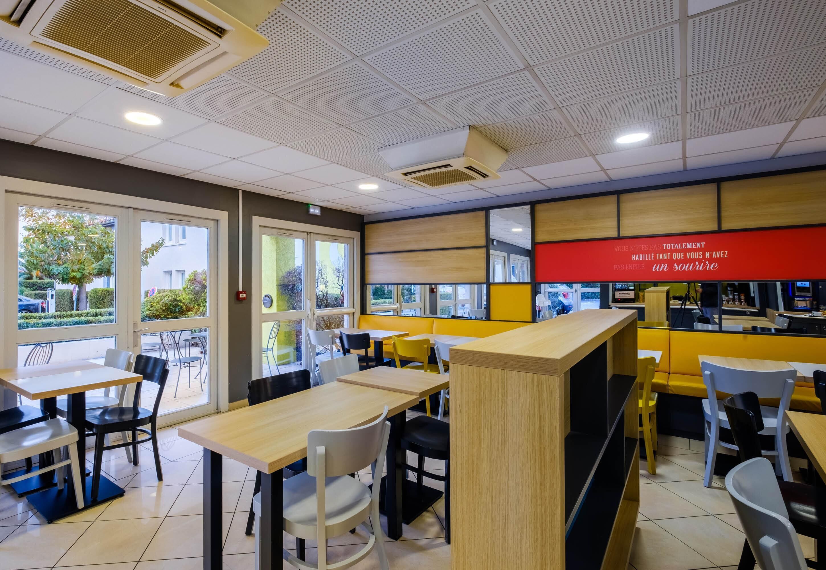 Un interior de restaurante con mesas, sillas, una barra y vistas a través de las ventanas.