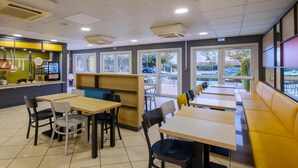 En restaurang med sittplatser inomhus, en bardisk och stora fönster.