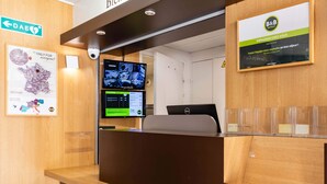 Un comptoir d’accueil avec un ordinateur, un écran affichant une carte et un panneau d’accueil.