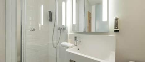 A modern bathroom with a glass-enclosed shower, a white sink, and a mirror above it.