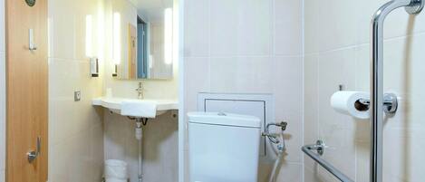 Une salle de bain équipée de toilettes, d’un lavabo et de barres d’appui.