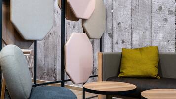 Un intérieur moderne avec un canapé gris, un coussin vert et deux petites tables rondes en bois.