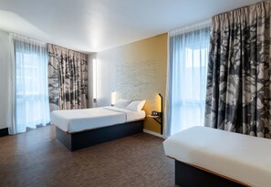 A hotel room with two beds, a wall-mounted nightstand, and sheer curtains. - B&B HOTEL Lille Villeneuve d'Ascq Grand Stade 3 étoiles (Villeneuve-d'Ascq)