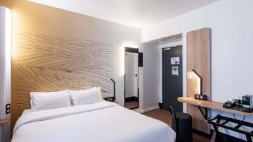 Hotelkamer met een bed, nachtkastje, bureau, stoel en een wand met een uniek ontwerp.