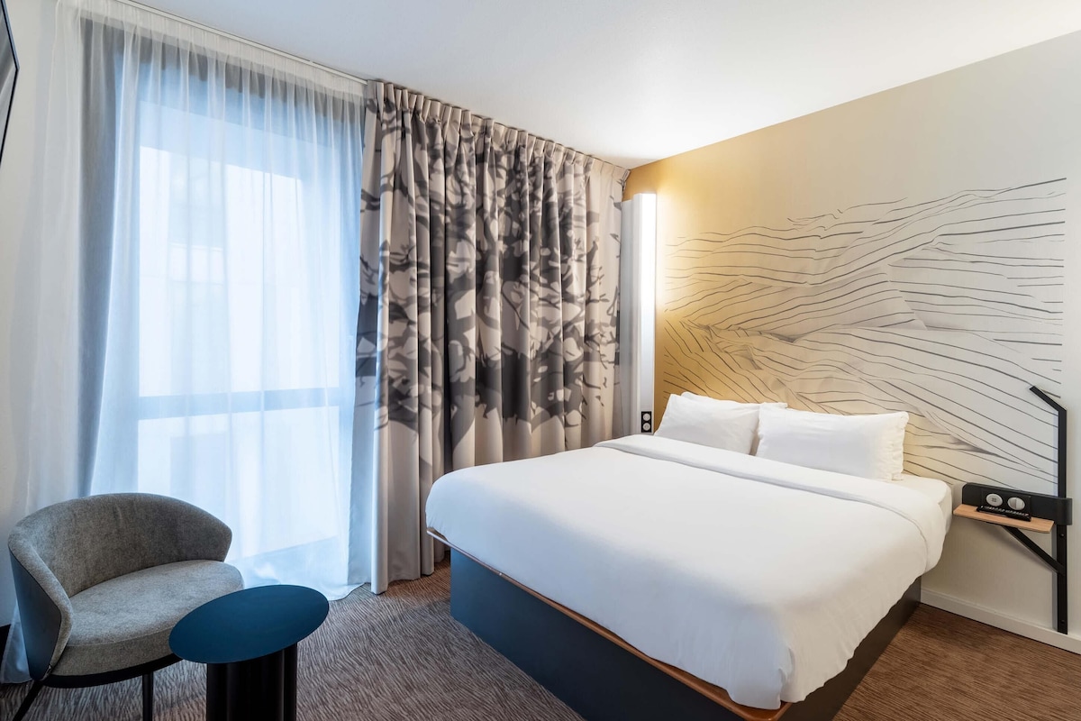Habitación de hotel con cama, una silla, un escritorio y una pared de diseño único.