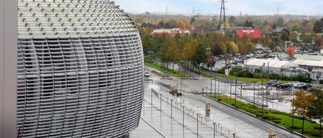 A modern building with a unique spherical design, a parking lot, and a road with traffic lights.