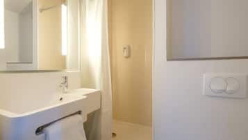 A bathroom with a sink, mirror, shower, and toilet.