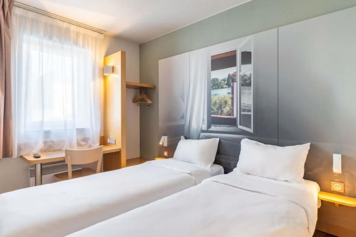 Une chambre d’hôtel avec deux lits, un bureau et une chaise.